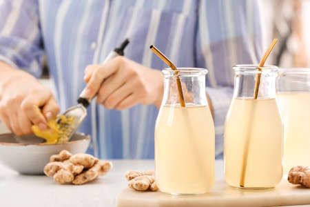 Bottles of healthy ginger juice on table in kitchenの写真素材