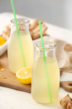 Bottles of healthy ginger juice on light background