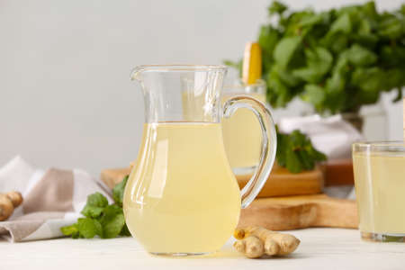 Jug of healthy ginger juice on light wooden backgroundの写真素材