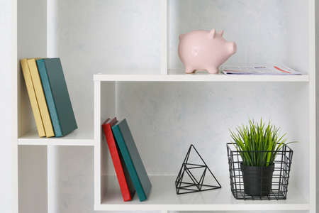Modern shelf unit with books and decor near light wallの写真素材
