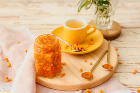 Tasty homemade sea buckthorn jam and cup of tea on tableの写真素材