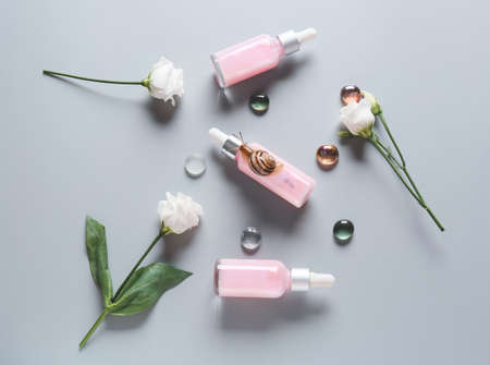Snail, cosmetics and flowers on gray backgroundの写真素材