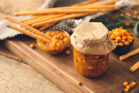 Tasty homemade sea buckthorn jam on table