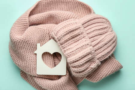 Figure of house and warm clothes on color background. Concept of heating seasonの写真素材