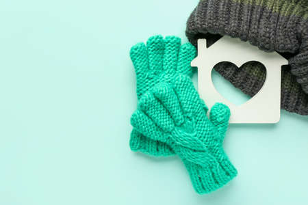 Figure of house and warm clothes on color background. Concept of heating seasonの写真素材