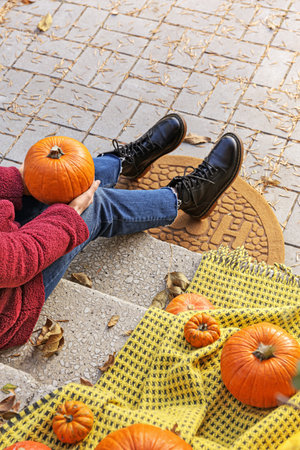 Woman with pumpkins sitting near entrance of house on autumn dayの写真素材
