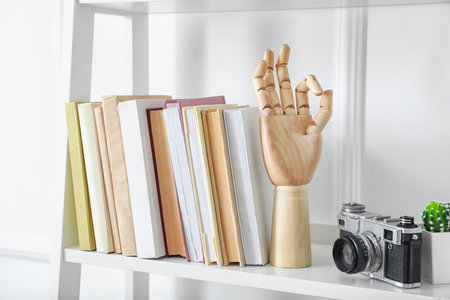 Shelf unit with books and decor near white wall in roomの写真素材