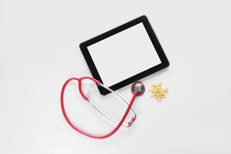 Stethoscope, folic acid pills and tablet computer on white background