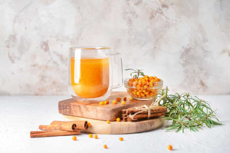 Cup of healthy sea buckthorn tea on light background