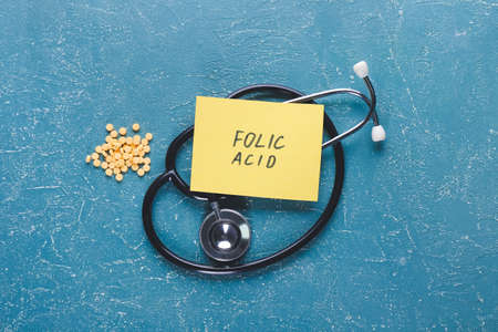 Stethoscope, text FOLIC ACID and pills on color background