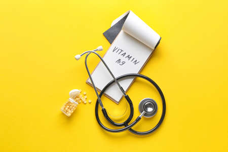 Stethoscope, bottle with folic acid pills and text VITAMIN B9 on color backgroundの写真素材