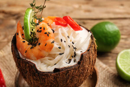 Coconut with Thai noodle soup on wooden background