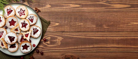 Plate with tasty Linzer cookies on wooden background with space for text