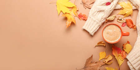 Autumn composition with cup of coffee, sweater and leaves on color backgroundの写真素材