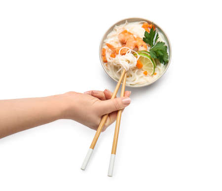 Woman eating Thai noodle soup on white backgroundの写真素材
