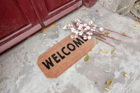 Doormat with cotton flowers near entrance of house on autumn dayの写真素材