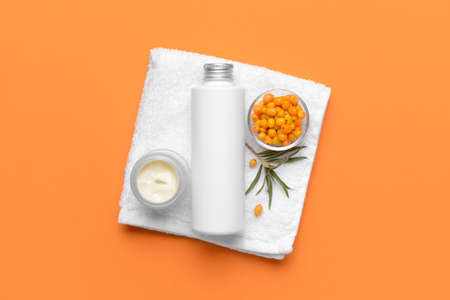 Healthy sea buckthorn cosmetics with towel on color backgroundの写真素材