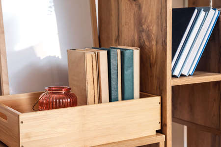 Modern shelf unit and wooden box with books, closeup