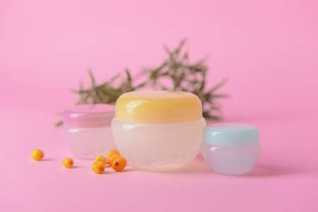 Jars of healthy sea buckthorn cream on color backgroundの写真素材