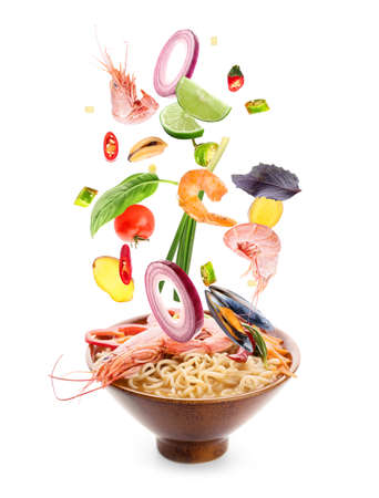 Bowl of tasty Thai soup with flying ingredients on white backgroundの写真素材