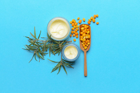 Jars of healthy sea buckthorn cream on color backgroundの写真素材
