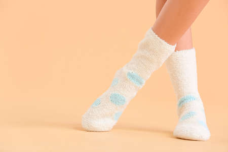 Legs of young woman in socks on color background