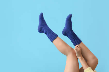 Young woman putting on socks against color backgroundの写真素材