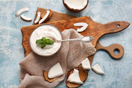 Bowl and spoon with coconut cream on color backgroundの写真素材