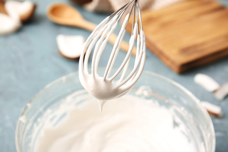 Bowl with coconut cream and whisk on color background, closeupの写真素材