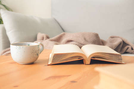 Old book and cup of tea on table in room, closeup