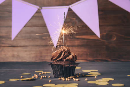 Tasty chocolate cupcake with sparkler on tableの写真素材