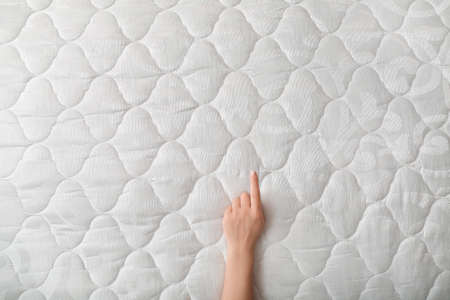Female hand on soft orthopedic mattress, top viewの写真素材