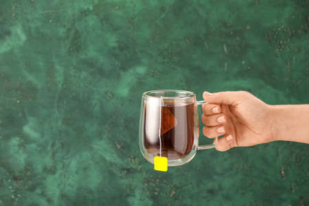 Woman with cup of hot black tea on color background