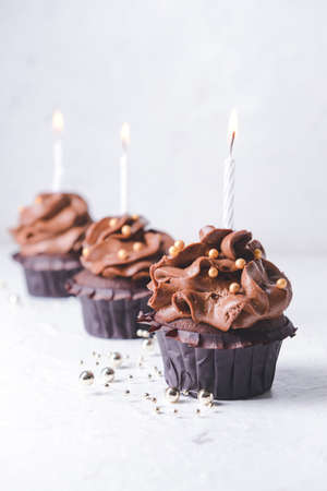 Tasty chocolate cupcakes with candles on light backgroundの写真素材