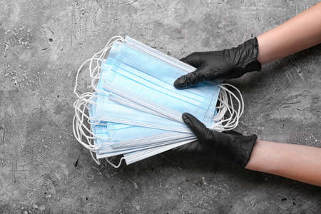 Female hands in protective gloves with medical masks on gray background