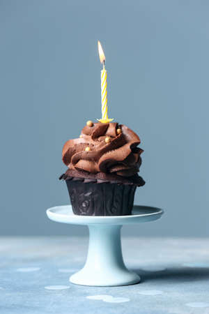 Tasty chocolate cupcake with candle on color background