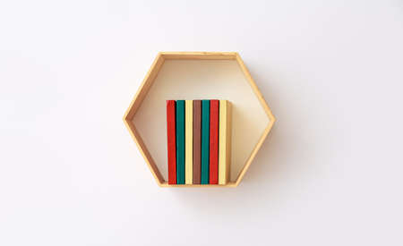 Shelf with books hanging on light wallの写真素材