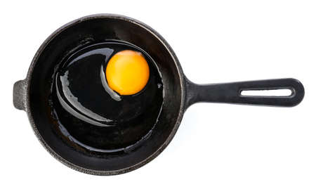 Frying pan with raw egg on white background