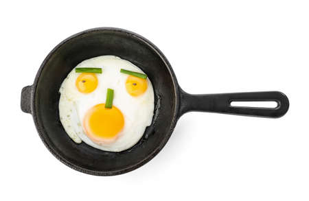 Frying pan with tasty eggs and onion on white backgroundの写真素材
