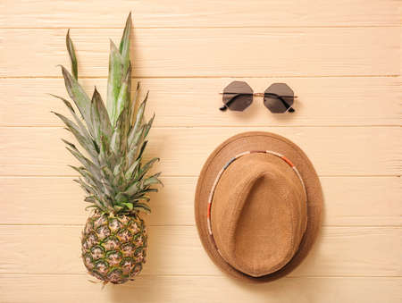 Stylish hat, sunglasses and pineapple on color wooden backgroundの写真素材