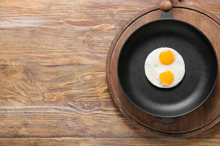 Frying pan with tasty eggs on wooden backgroundの写真素材