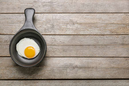 Frying pan with tasty egg on wooden backgroundの写真素材