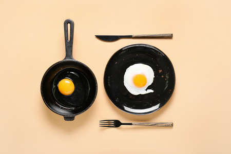 Frying pans with tasty eggs on color background