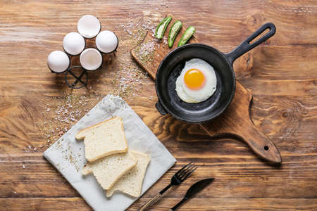 Frying pan with tasty egg on table