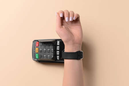 Female hand with smart watch and payment terminal on color backgroundの写真素材