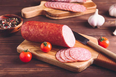 Tasty salami and tomatoes on wooden background