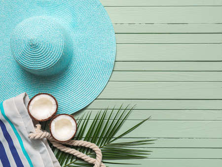 Stylish hat, bag, coconut and palm leaf on color wooden backgroundの写真素材