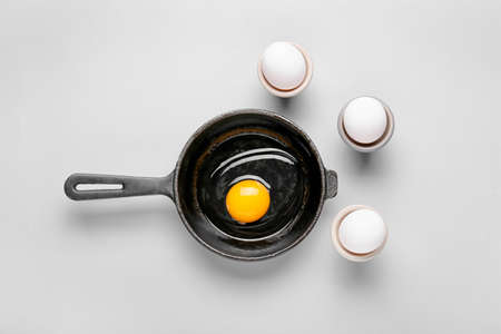 Frying pan with raw egg on light backgroundの写真素材