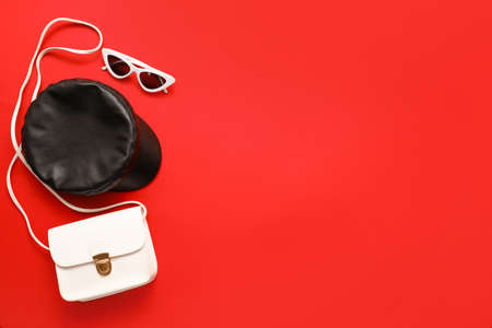 Stylish cap, bag and sunglasses on color background