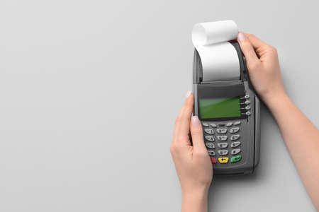 Female hands with payment terminal on light background